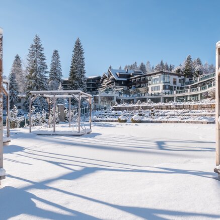 Verschneite Landschaft mit Hotelanlage und Pavillon im Winter unter blauem Himmel